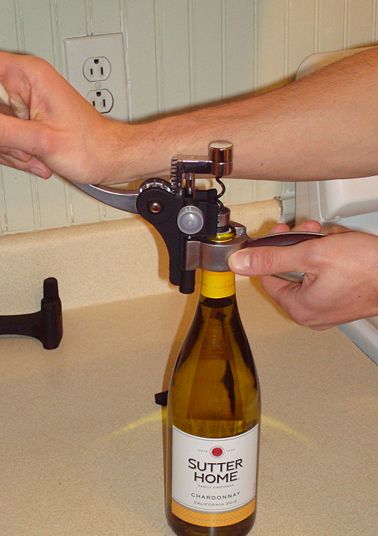 Pulling down the lever arm. The cork is penetrated by the screw