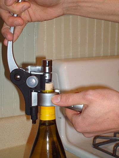 Pulling up the lever arm. The cork is pulled out of the bottleneck