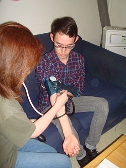 A First Responder practices taking a patient's blood pressure using a blood pressure cuff and a stethoscope.