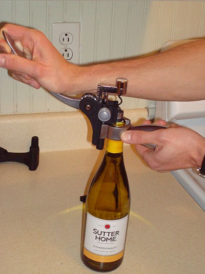 Pulling down the lever arm. The cork is penetrated by the screw